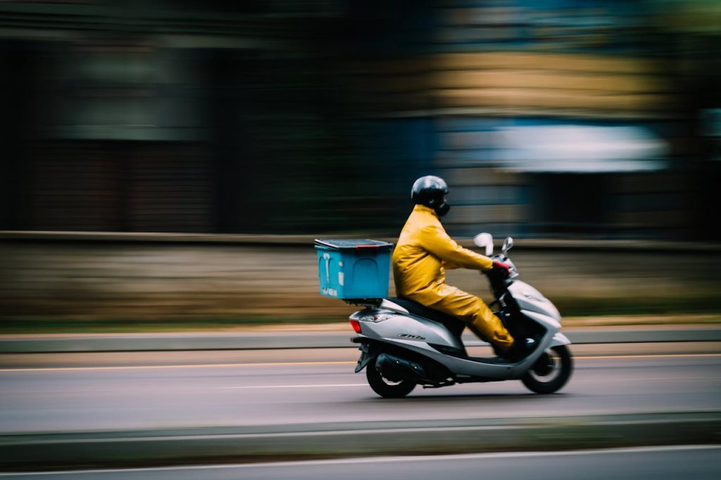 A courier riding a scooter rapidly down the road, symbolizing efficient and quick delivery services.